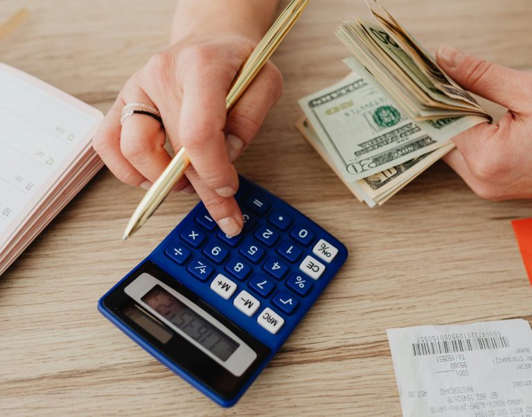Hands handling cash and calculator for budget planning. Modern financial scene.